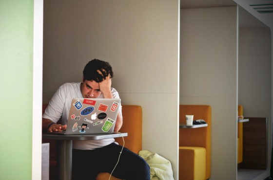 Man met gebogen hoofd achter laptop.